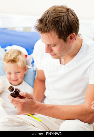 Attractive father giving cough syrup to his sick son Stock Photo