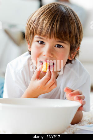 Cute little boy eating chips lying on the floor Stock Photo