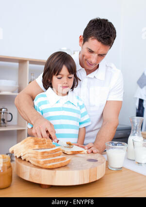 Charming father and his son spreading jam on bread Stock Photo