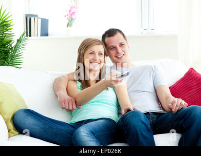 Charismatic man embracing his girlfriend while watching tv Stock Photo