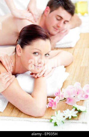 Relaxed young beautiful couple receiving a back massage from masseur in