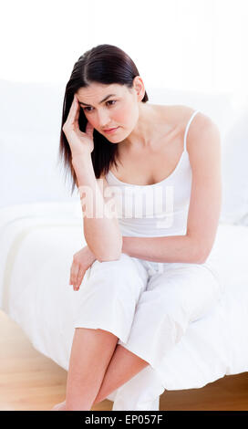Portrait of a unhappy woman sitting on bed Stock Photo