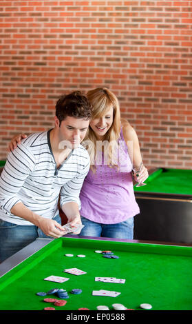 Cheerful couple playing cards on a billiard Stock Photo