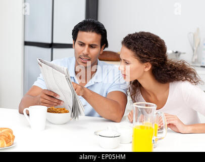 Serious man showing the newspaper to his wife during breakfast Stock Photo