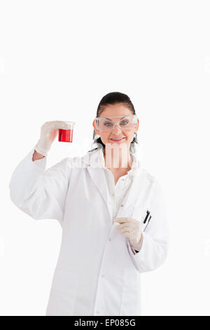 Dark-haired scientist looking at the camera while holding a red beaker Stock Photo