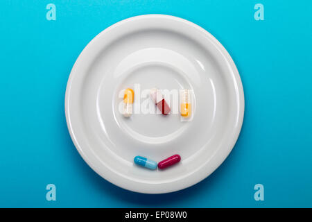5 capsules on a plate on a blue background Stock Photo