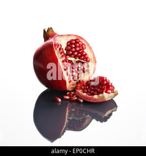 Pomegranate opened up on reflective surface (Punica granatum) Stock Photo