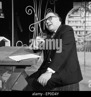 Deutscher Komiker und Wortspieler Heinz Erhardt mit einem Glas Wein, Anfang 1960er Jahre. German comedian and master of pun, Stock Photo