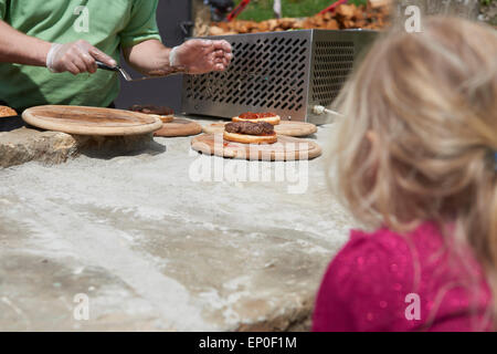 Child girl looking cook at work cooking hamburger in open air grill restaurant Stock Photo