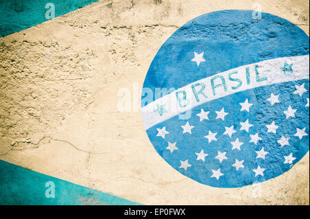 Weathered painted mural of Brazilian flag on textured stone wall Stock Photo