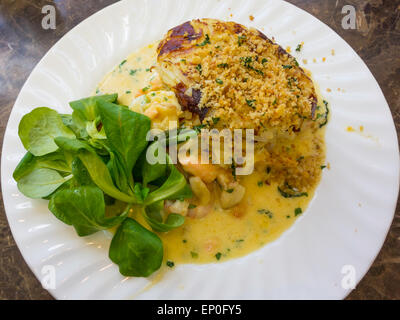 Lunch, Haddock Salmon and prawn gratin in white wine sauce on wilted spinach with potato rosti and seasoned breadcrumb topping Stock Photo