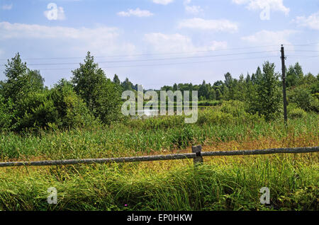 Rural landscape - log fence near lake in village. Stock Photo