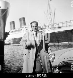 Ein Mann steht an seinem Auto der Marke Studebaker Packard im Hafen von Hamburg und raucht seine Pfeife, 1954. A man standing by Stock Photo