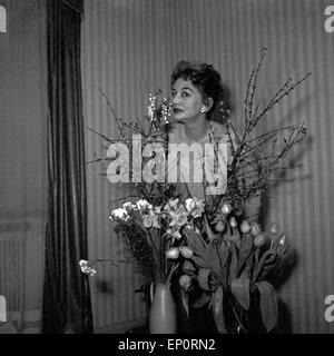 Deutsche Sängerin, Schauspielerin und Tänzerin Evelyn Künneke hinter Blumensträußen, Deutschland 1956. German actress, singe Stock Photo