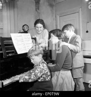 Kinder lernen bei ihrer Klavierlehrerin Klavier spielen, Hamburg 1956. Children learn to play piano with their teacher. Stock Photo
