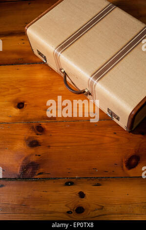 A vintage suitcase sits on a wood floor. Stock Photo