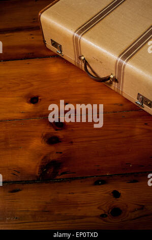 A vintage suitcase sits on an old wood floor. Stock Photo
