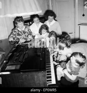 Kinder lernen bei ihrer Klavierlehrerin Klavier spielen, Deutschland 1950er Jahre. Stock Photo