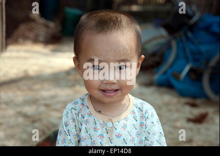 A portrait of a happy smiling young Burmese baby boy with sandalwood cosmetic sunscreen on his face on Ngapali beach Myanmar Stock Photo