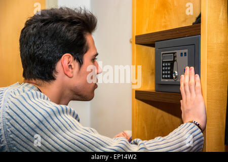 Young handsome man using a small vault or safe in his home Stock Photo