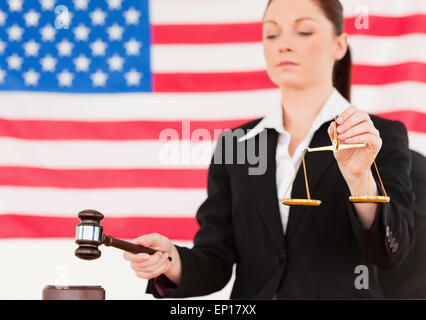 Close up of a young judge knocking a gavel and holding scales of justice Stock Photo