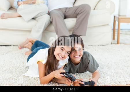 Children playing videogames while parents are talking Stock Photo