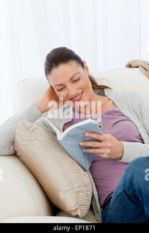 Cute woman reading a romance sitting on the sofa Stock Photo