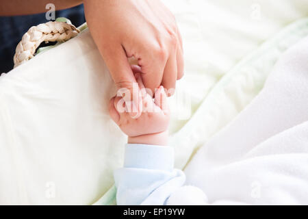 Close-up of a young mother holding her baby's hand Stock Photo
