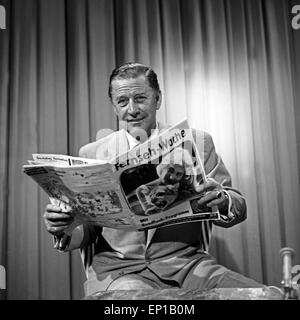 Deutscher Schauspieler Hans Söhnker wirft einen Blick in die Zeitschrift 'TV Fernsehwoche', Deutschland 1950er Jahre. German Stock Photo
