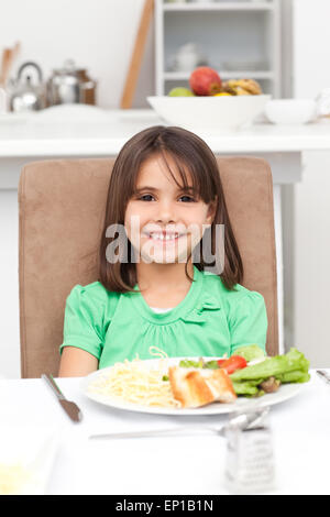 Cute little girl eating pasta and salad Stock Photo