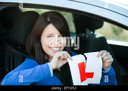 Jolly teen girl sitting in her car tearing a L-sign Stock Photo