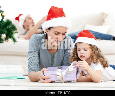Mother and daughter unwrapping a present lying on the floor Stock Photo