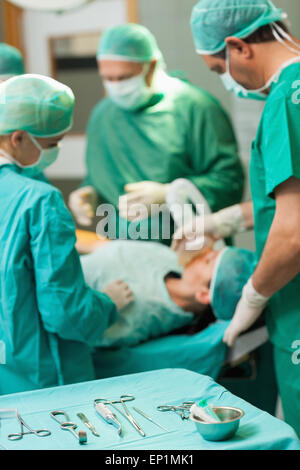 Table full of surgical tools in front of a surgical team working Stock Photo