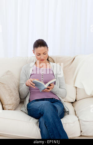Attentive woman reading a book on the sofa Stock Photo