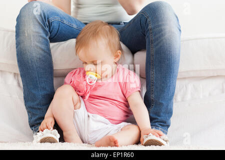 Baby playing with her mother's feet while sitting on a carpet Stock Photo