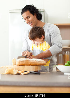 Attentive father helping his son cut some bread Stock Photo