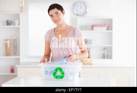 Smiling Woman putting bottles in a recycling box Stock Photo
