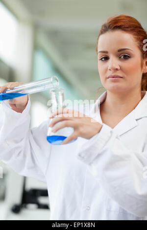 Portrait of a cute scientist pouring blue liquid in an Erlenmeye Stock Photo