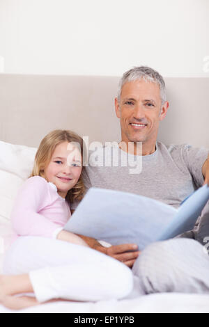 Portrait of a father reading a story to his daughter Stock Photo