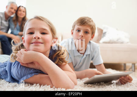 Happy siblings using a tablet computer with their parents on the Stock Photo
