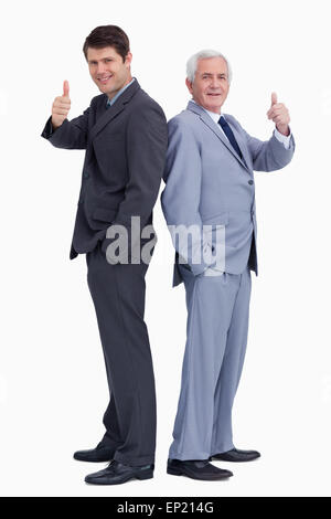 Businessmen standing back to back giving thumbs up Stock Photo