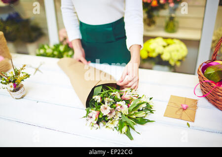 Female florist wrapping up bouquet of white amaryllises Stock Photo