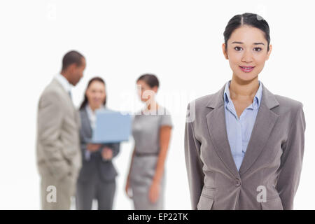 Businesswoman with co-workers watching a laptop in the background Stock Photo