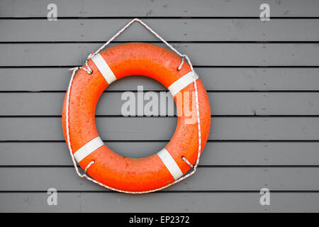 Red lifebuoy hanging on gray wooden wall of a port building Stock Photo