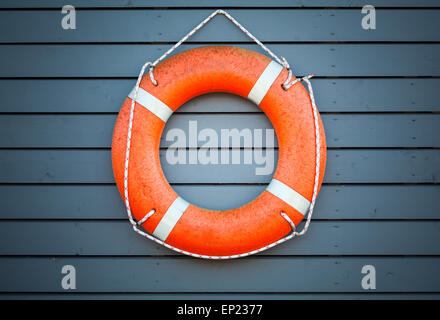 Red lifebuoy hanging on blue wooden wall of a port building Stock Photo