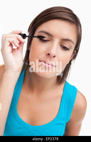Young woman almost closing her eyes while applying mascara Stock Photo