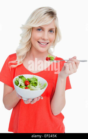 Young smiling woman eating a fresh salad with a fork Stock Photo