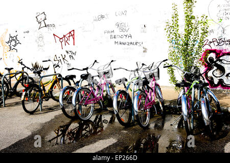 Bicycles parked against the graffiti covered wall behind Berlin's East Side Gallery on Mühlenstraße in Friedrichshain-Kreuzberg. Stock Photo