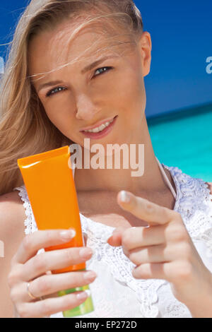 Portrait of woman holding sunscreen cream on beach, beauty concept Stock Photo