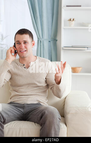 Portrait of a man talking through the phone while sitting on a c Stock Photo